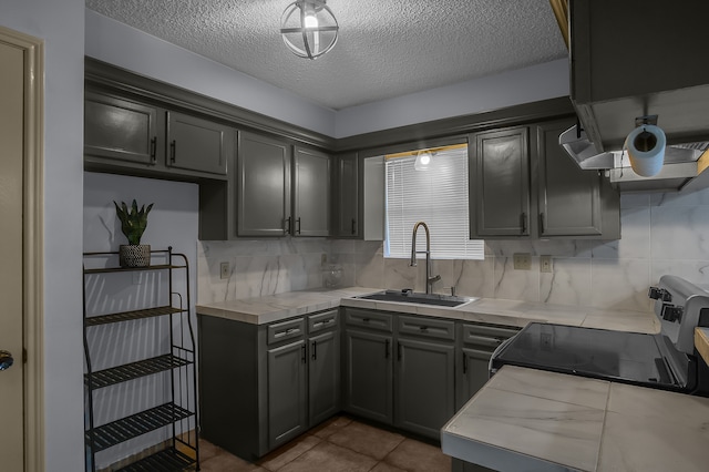 kitchen featuring gray cabinetry, sink, backsplash, a textured ceiling, and electric stove