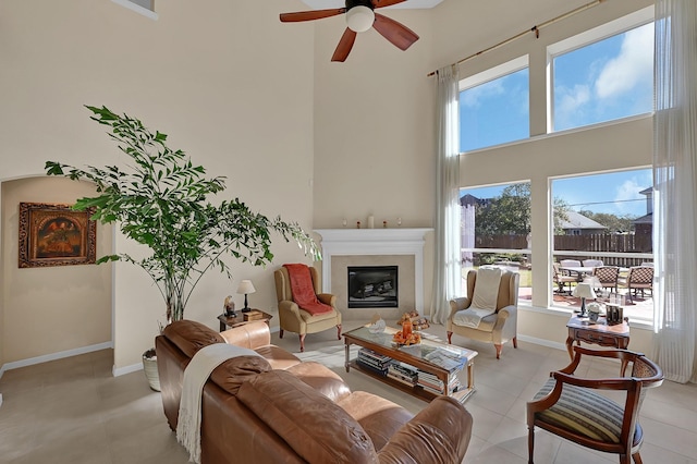 tiled living room with ceiling fan, a healthy amount of sunlight, and a high ceiling