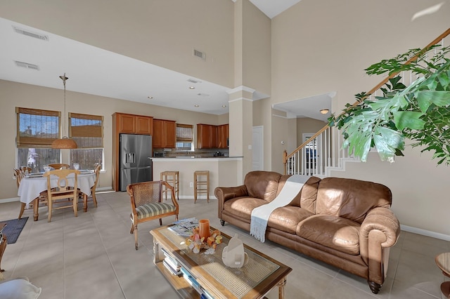 living room with light tile patterned floors, a towering ceiling, and decorative columns