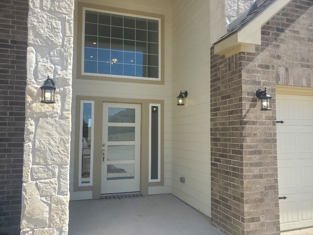 doorway to property with a garage and brick siding