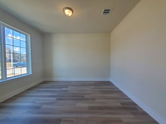 spare room featuring visible vents, baseboards, and wood finished floors