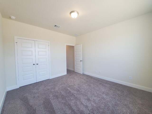 unfurnished bedroom with a closet, carpet flooring, visible vents, and baseboards