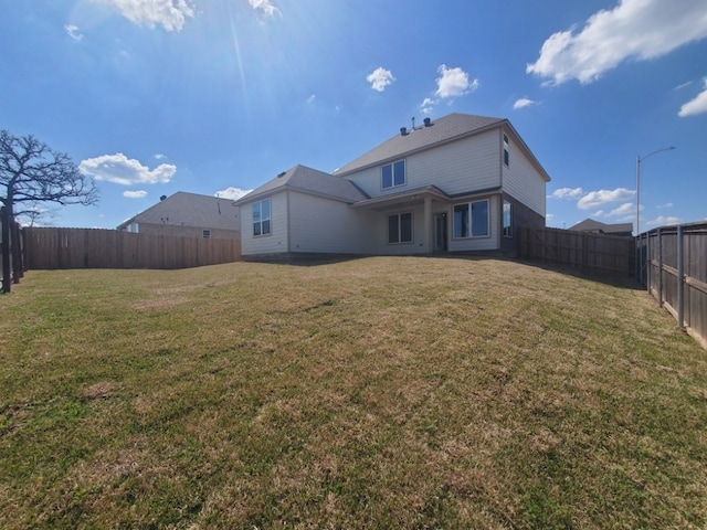 back of property with a fenced backyard and a yard