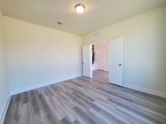 spare room featuring baseboards, visible vents, and wood finished floors