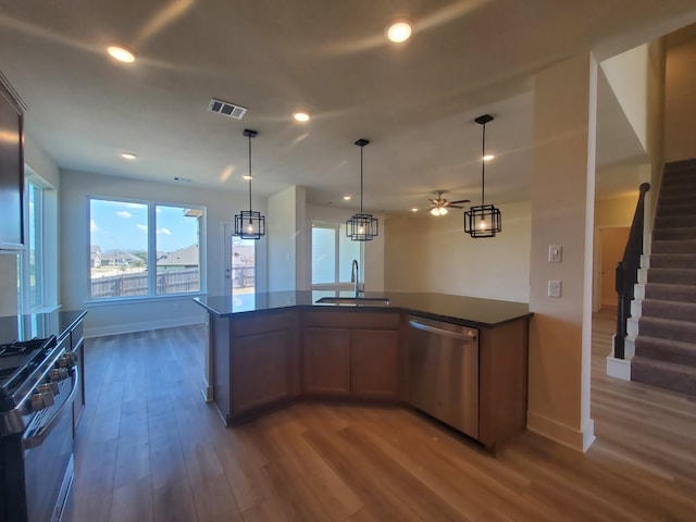 kitchen with range with gas stovetop, dark countertops, visible vents, a sink, and dishwasher