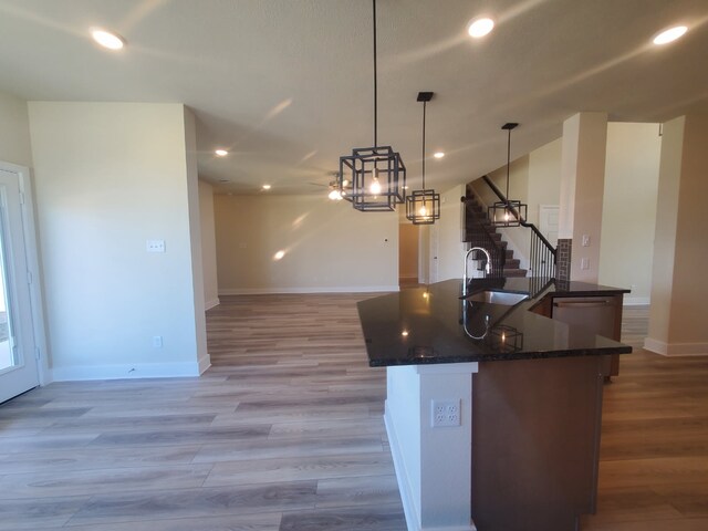 kitchen with light wood finished floors, recessed lighting, stainless steel dishwasher, open floor plan, and a sink