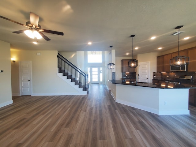 kitchen featuring dark wood-style flooring, baseboards, appliances with stainless steel finishes, backsplash, and dark countertops