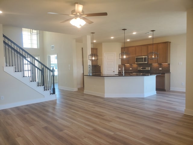 kitchen with appliances with stainless steel finishes, dark countertops, light wood-style flooring, and tasteful backsplash