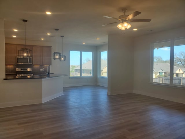 kitchen featuring stainless steel appliances, dark countertops, backsplash, and dark wood-style floors