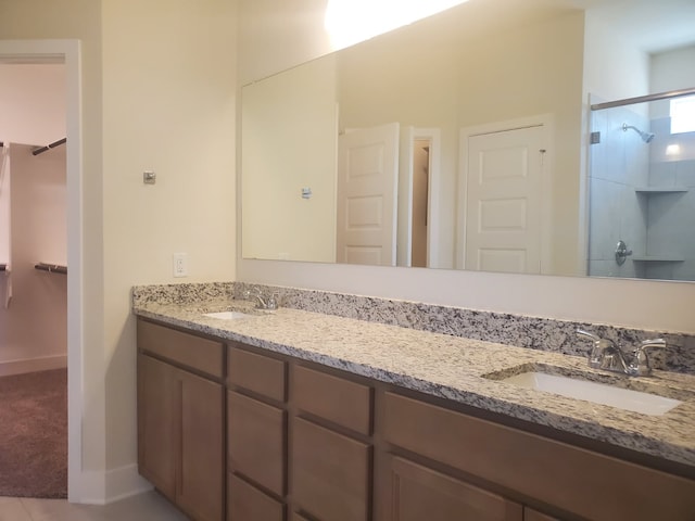 full bath featuring a shower, double vanity, a spacious closet, and a sink