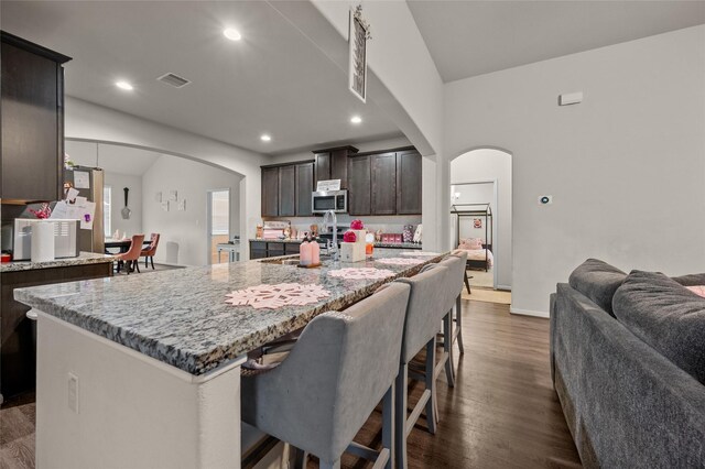 kitchen with lofted ceiling, dark hardwood / wood-style flooring, a kitchen island, and dark brown cabinets