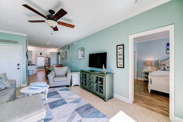 living room featuring ceiling fan, ornamental molding, and light tile patterned flooring