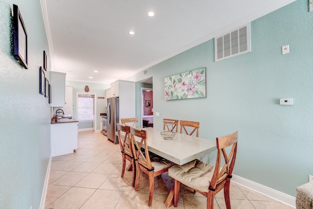 tiled dining space featuring ornamental molding and sink