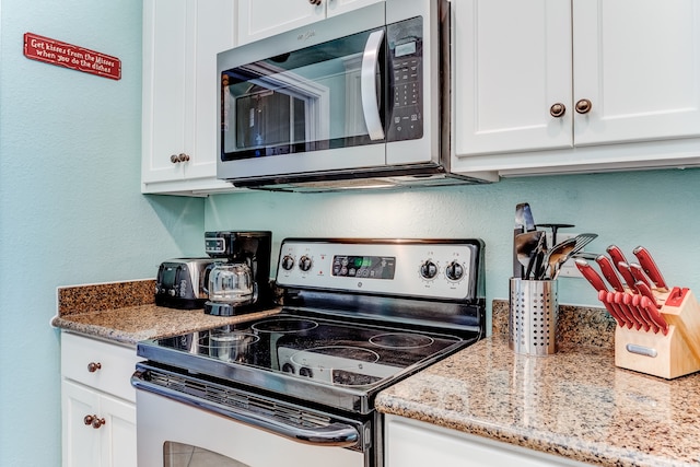 kitchen featuring white cabinets, stainless steel appliances, and light stone counters