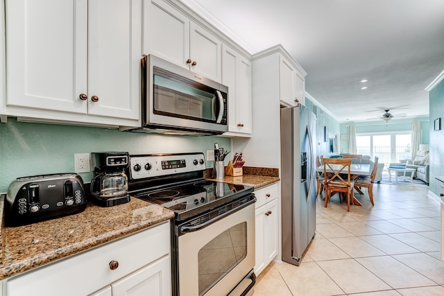 kitchen with appliances with stainless steel finishes, white cabinetry, light stone counters, and ceiling fan