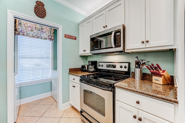 kitchen with white cabinets, dark stone countertops, ornamental molding, and stainless steel appliances