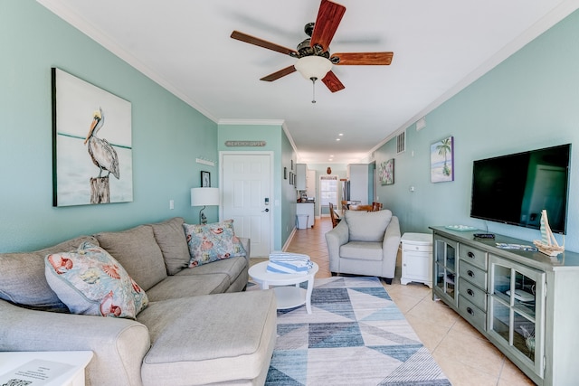 tiled living room with ceiling fan and crown molding