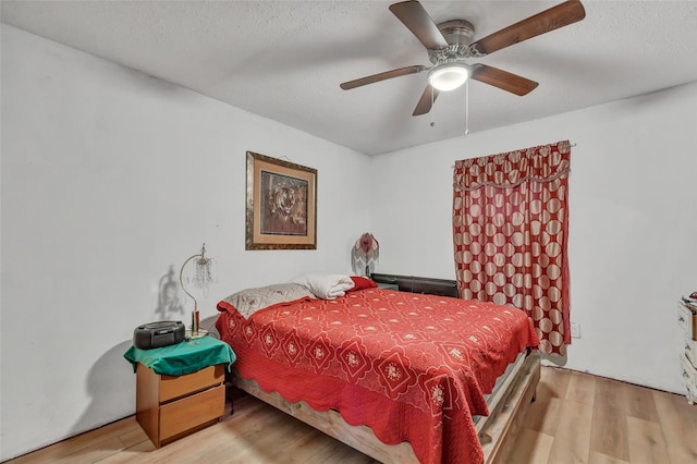 bedroom with ceiling fan, a textured ceiling, and light hardwood / wood-style flooring