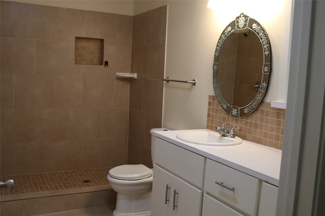 bathroom with tasteful backsplash, tile patterned floors, a tile shower, vanity, and toilet