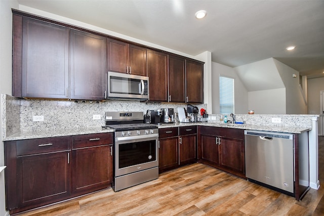 kitchen with light stone counters, light hardwood / wood-style flooring, stainless steel appliances, and dark brown cabinets