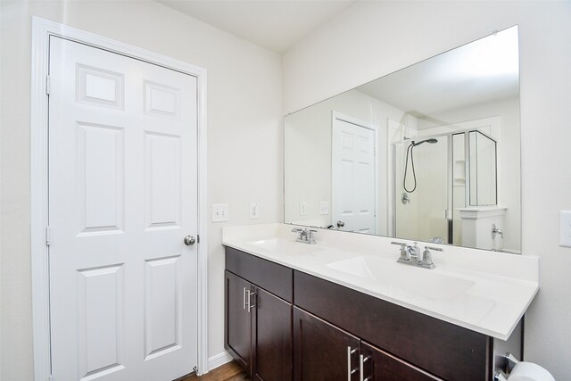 bathroom featuring a shower with door and vanity