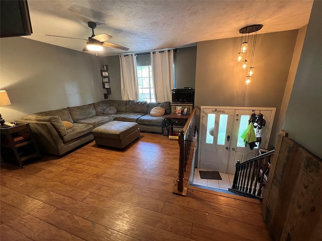 living room featuring a textured ceiling, light wood-type flooring, and ceiling fan