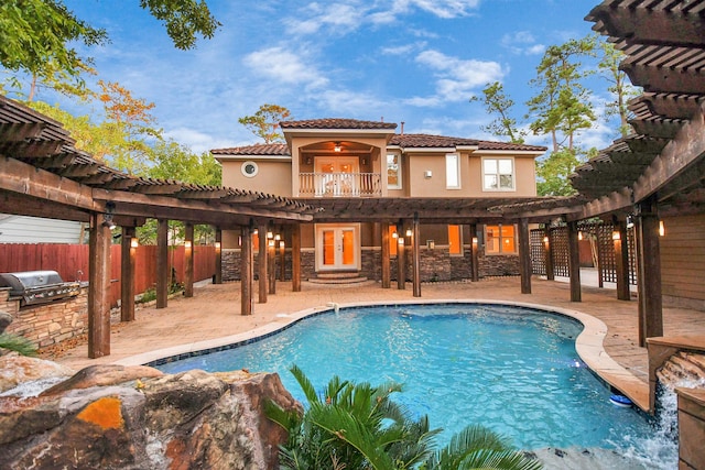 view of pool with french doors, an outdoor kitchen, a pergola, area for grilling, and ceiling fan