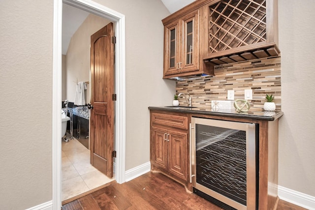 bar with decorative backsplash, dark hardwood / wood-style flooring, vaulted ceiling, beverage cooler, and sink