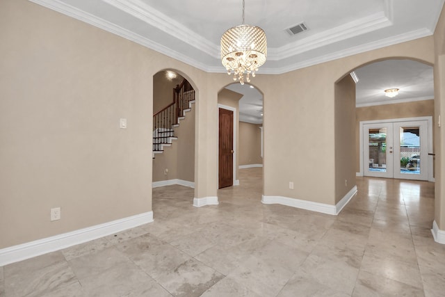 unfurnished room with a chandelier, french doors, a tray ceiling, and ornamental molding