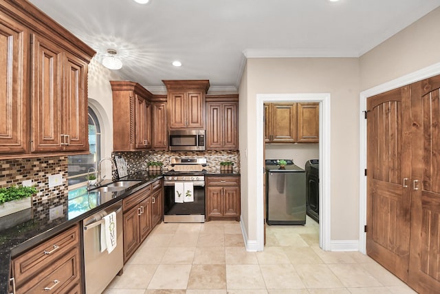 kitchen featuring sink, tasteful backsplash, independent washer and dryer, dark stone counters, and appliances with stainless steel finishes