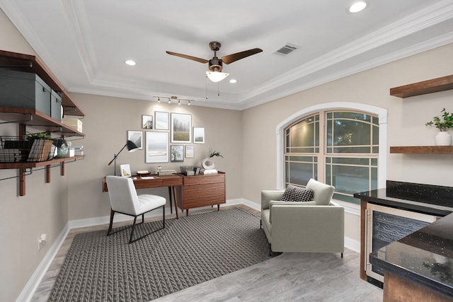 office area featuring ceiling fan, a raised ceiling, crown molding, and light hardwood / wood-style flooring