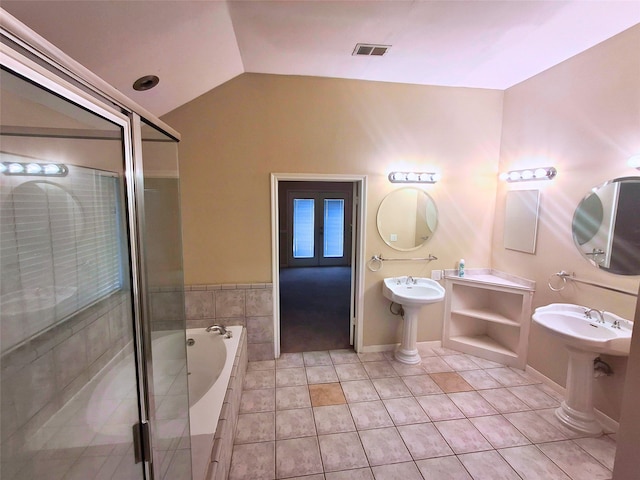 bathroom featuring lofted ceiling, tile patterned flooring, tiled tub, and double sink