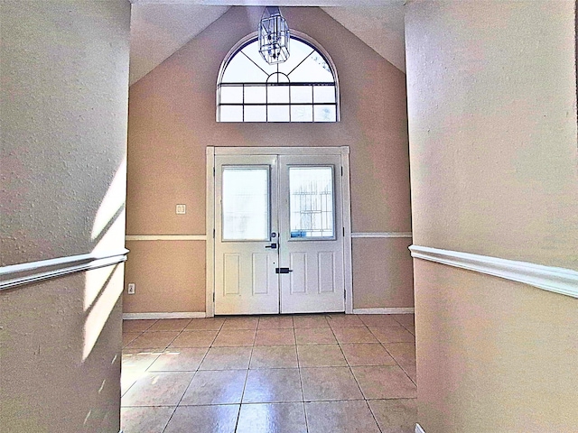 entryway featuring an inviting chandelier, light tile patterned flooring, and vaulted ceiling