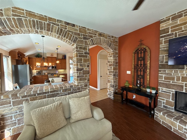 living room with a fireplace, hardwood / wood-style floors, lofted ceiling, and a notable chandelier