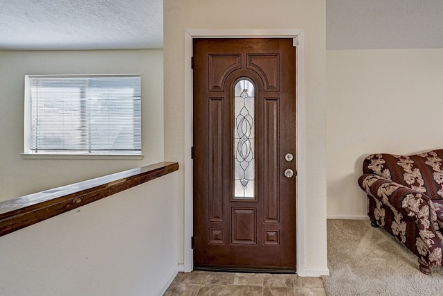 foyer entrance featuring light colored carpet and a textured ceiling