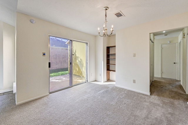 unfurnished room with carpet floors, a textured ceiling, and an inviting chandelier