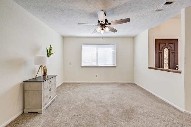 carpeted spare room with ceiling fan and a textured ceiling