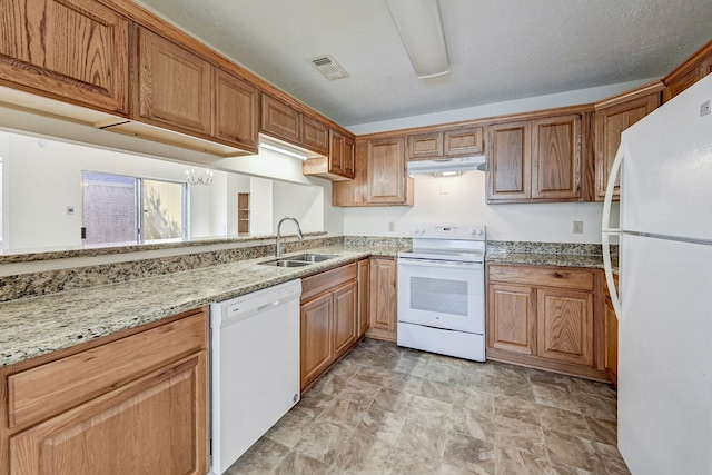 kitchen with light stone counters, a textured ceiling, white appliances, sink, and a notable chandelier