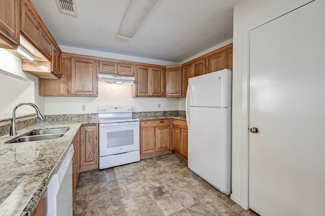 kitchen featuring a textured ceiling, white appliances, light stone counters, and sink