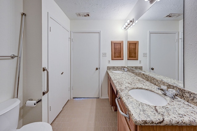 bathroom featuring vanity, a textured ceiling, and toilet