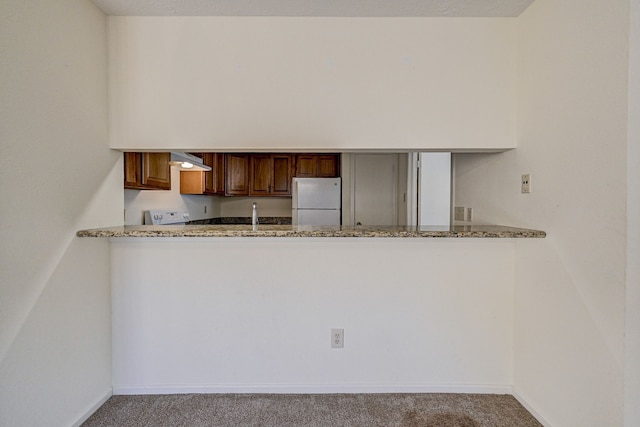 kitchen with carpet flooring, light stone counters, exhaust hood, and white appliances