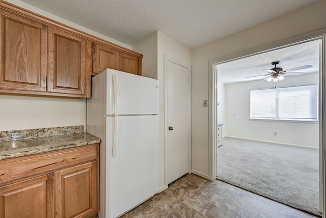 kitchen featuring ceiling fan, white fridge, light carpet, and a textured ceiling