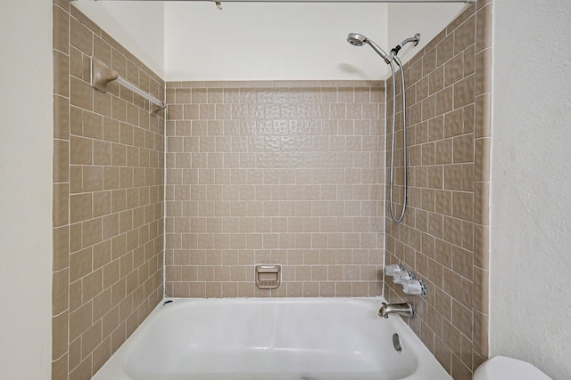 bathroom with toilet and tiled shower / bath