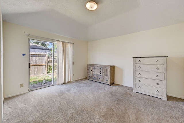 unfurnished bedroom featuring access to outside, a textured ceiling, and light colored carpet