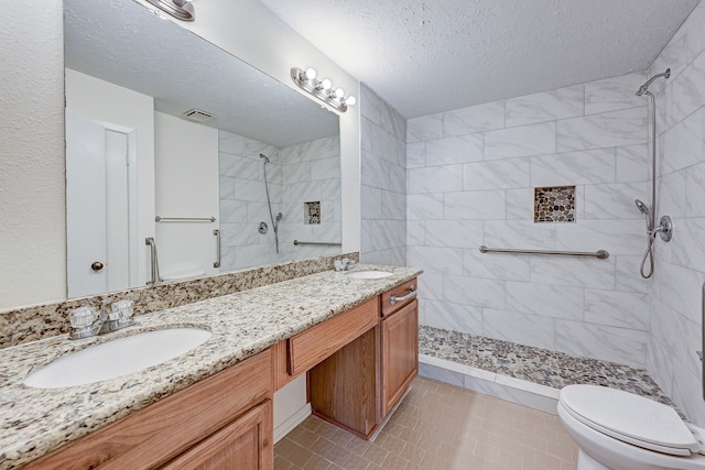 bathroom with a tile shower, tile patterned floors, a textured ceiling, toilet, and vanity