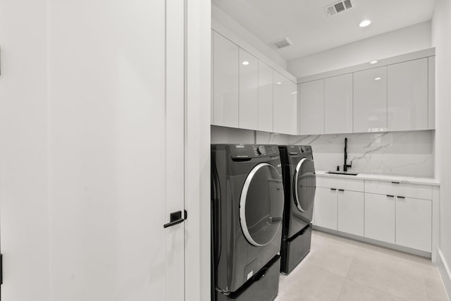 clothes washing area featuring cabinets, light tile patterned floors, washing machine and dryer, and sink