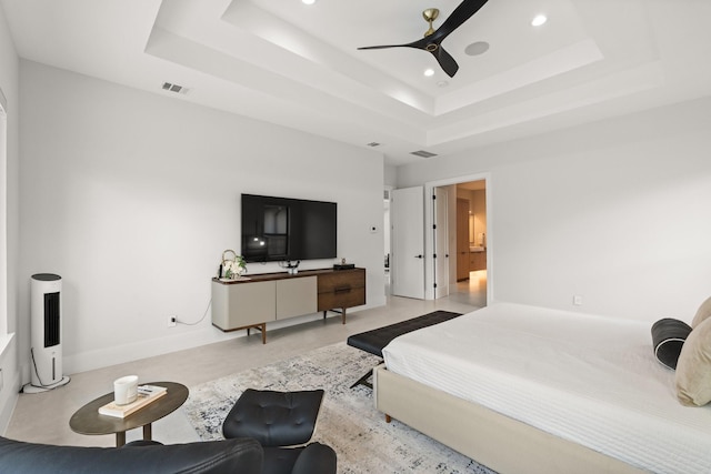 bedroom with ceiling fan, a raised ceiling, and ensuite bathroom