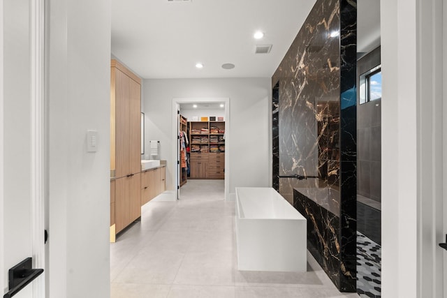 bathroom with tile patterned flooring, vanity, walk in shower, and tile walls