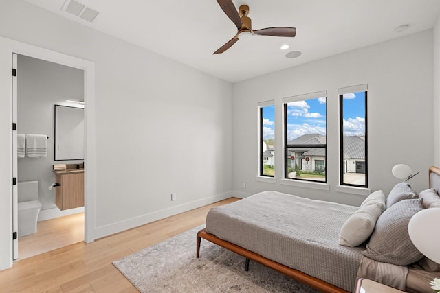 bedroom featuring ceiling fan, ensuite bathroom, and light wood-type flooring