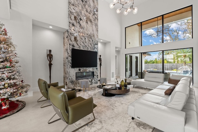 living room with a fireplace, a towering ceiling, and an inviting chandelier